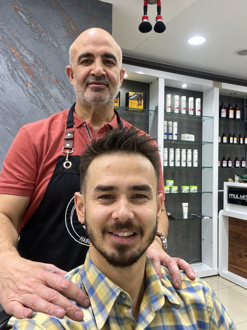 Ali Bey, yeni kesimli ve gülümseyen bir müşterinin arkasında duruyor
